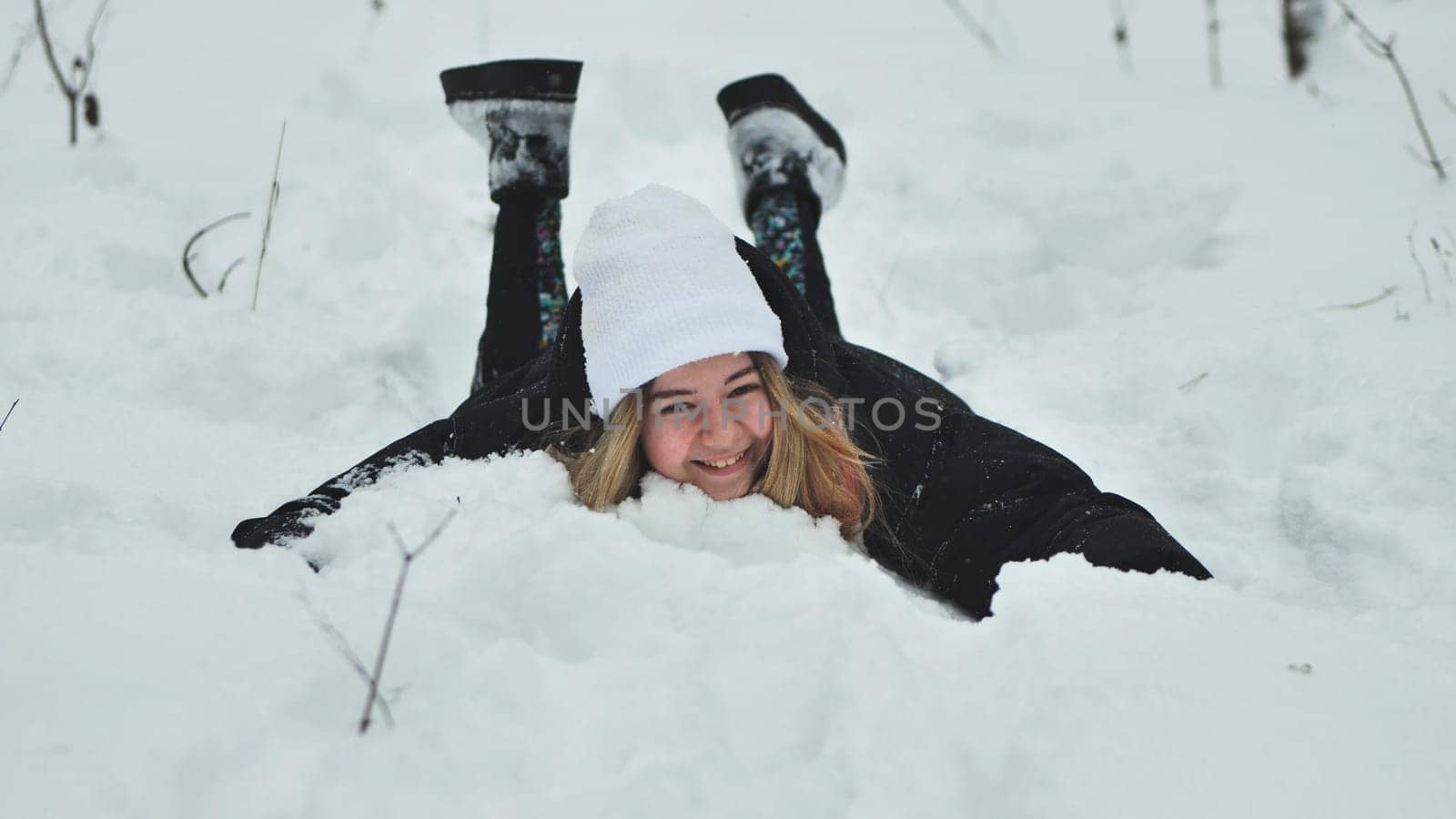 A girl falls on the snow in winter in the forest