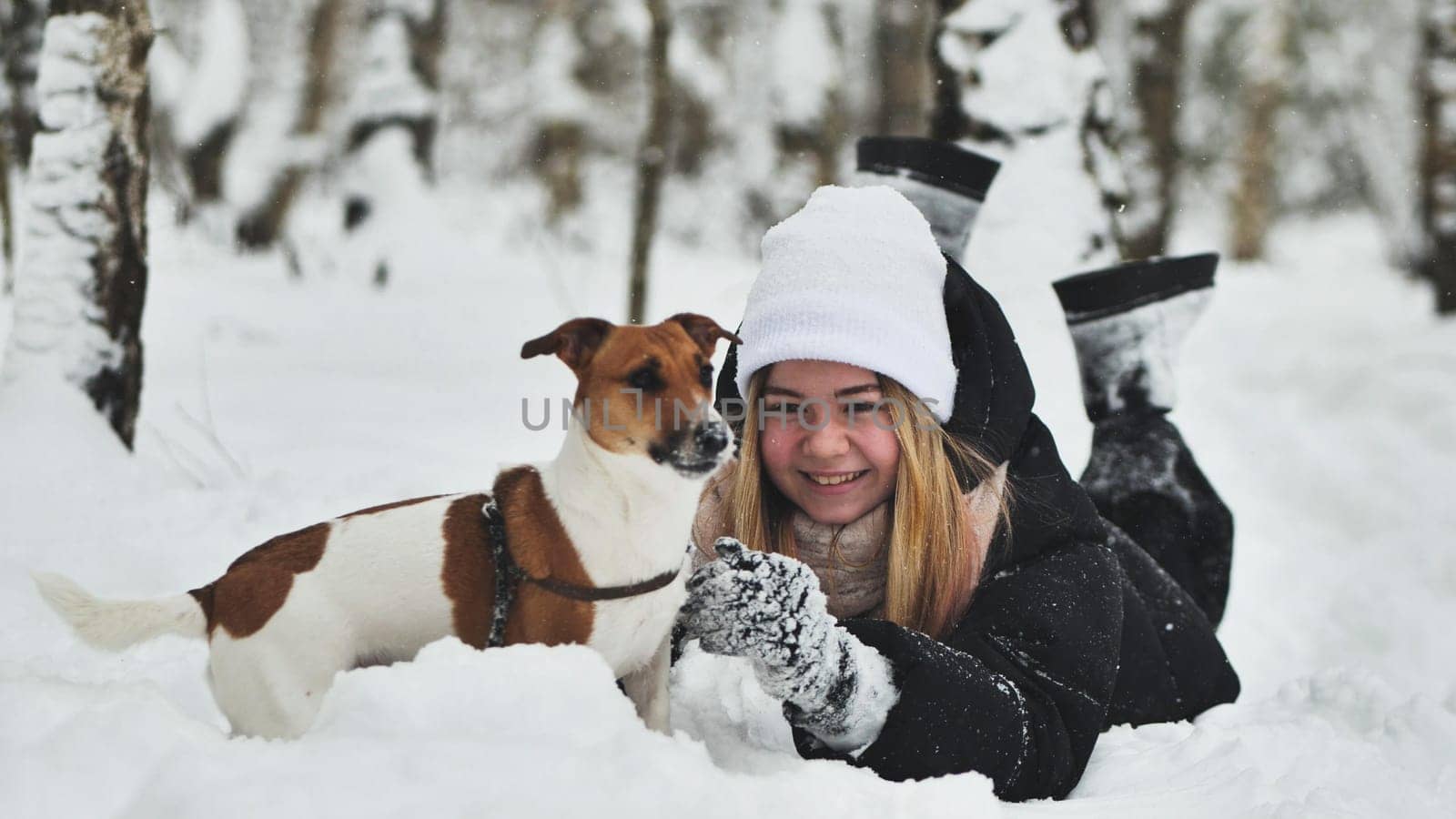 A girl playing with her Jack Russell Terrier dog in the snow