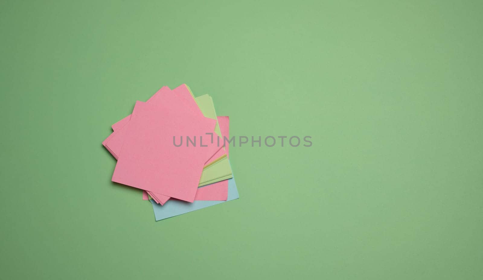 Stack of paper blank stickers on green background, top view by ndanko