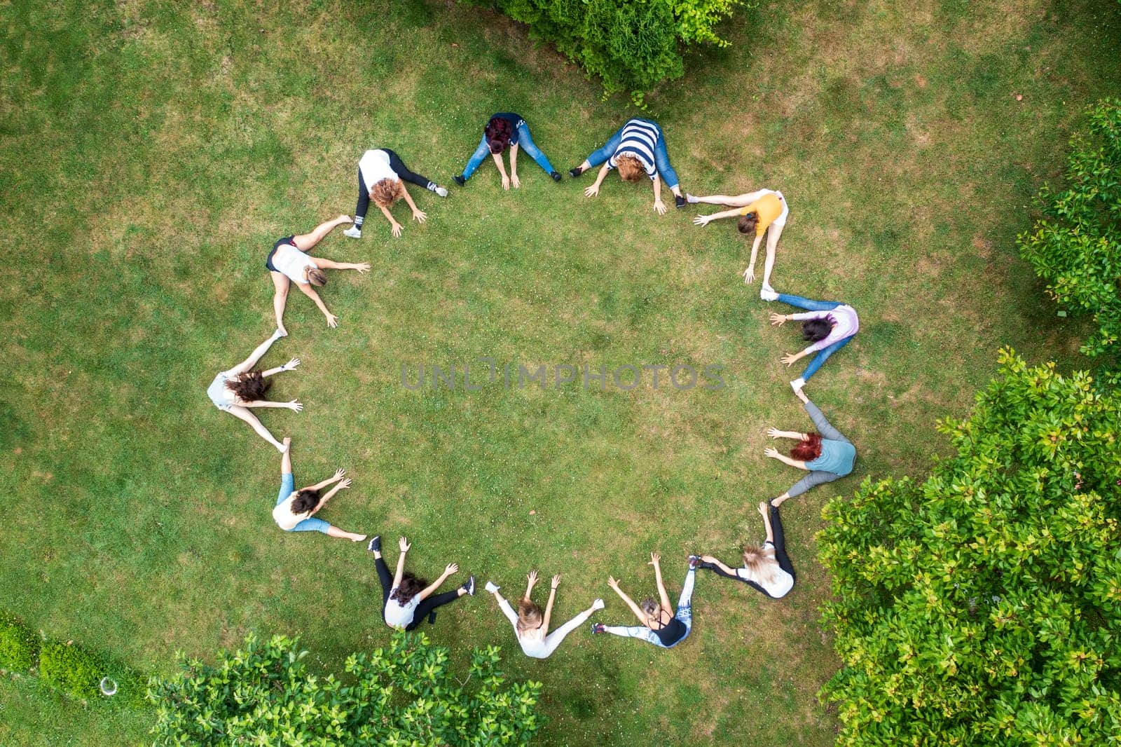 Top view of people standing in circle on green grass doing exercises