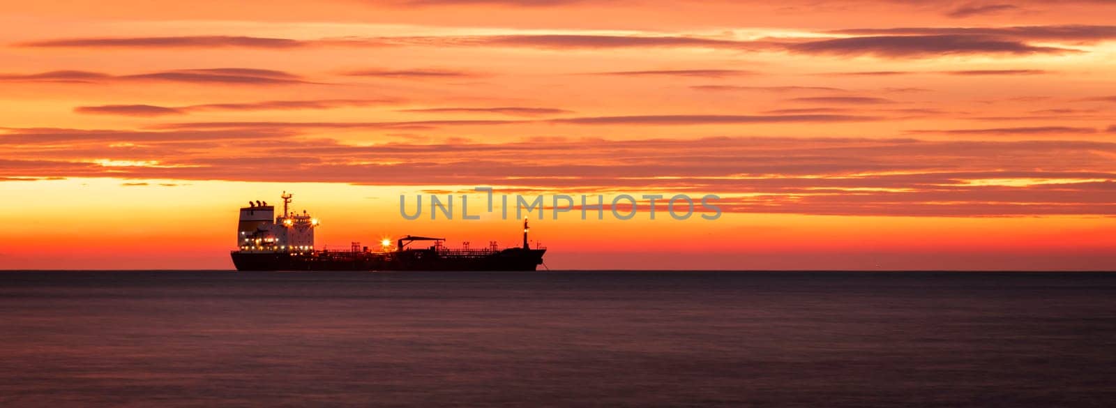 Silhouette of cargo Ship at horizon against of Amazing red sunrise by EdVal