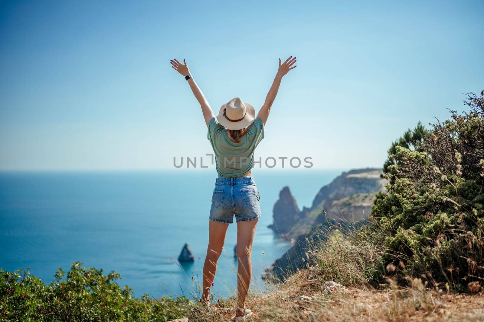 Woman tourist sky sea. Happy traveller woman in hat enjoys vacation raised her hands up by Matiunina