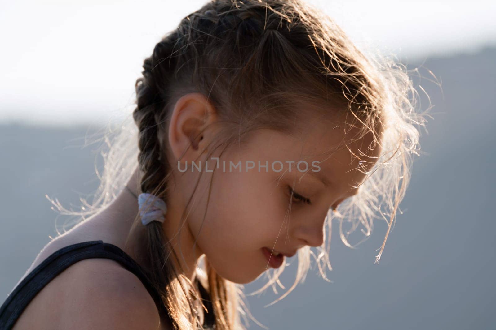 A young girl with braided hair is looking at the camera. She has a red lip and her hair is wet