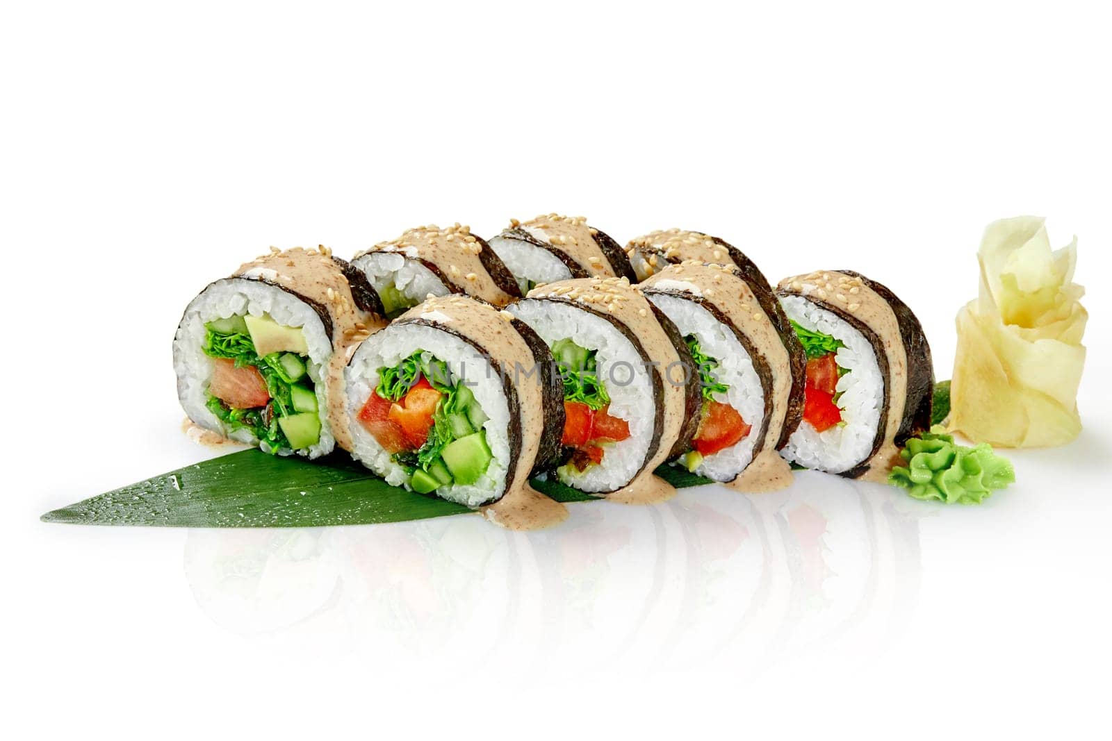 Appetizing Japanese style vegetarian sushi rolls with lettuce, bell pepper, cucumber, tomato, avocado and hiyashi wakame seasoned with piquant peanut sauce served on bamboo leaf with ginger and wasabi