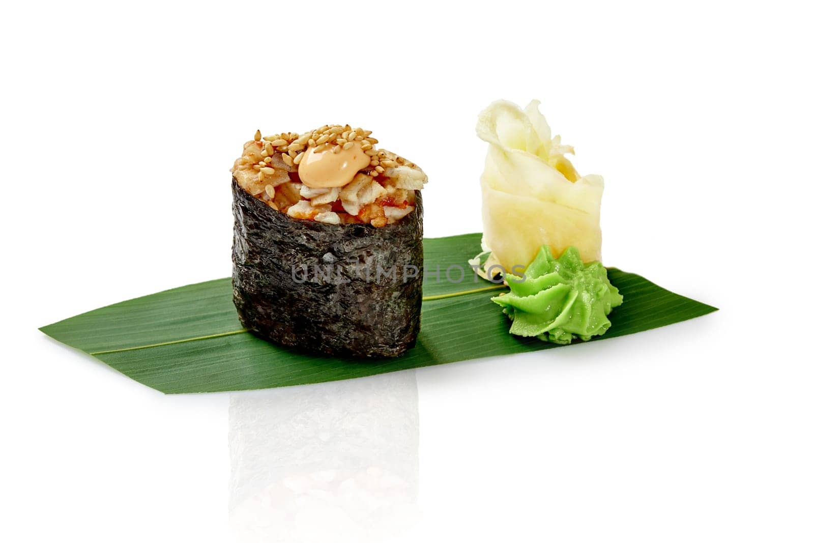 Gunkan maki sushi with eel seasoned with spicy sauce and sesame, presented with wasabi and pickled ginger on bamboo leaf, isolated on white background. Traditional Japanese cuisine