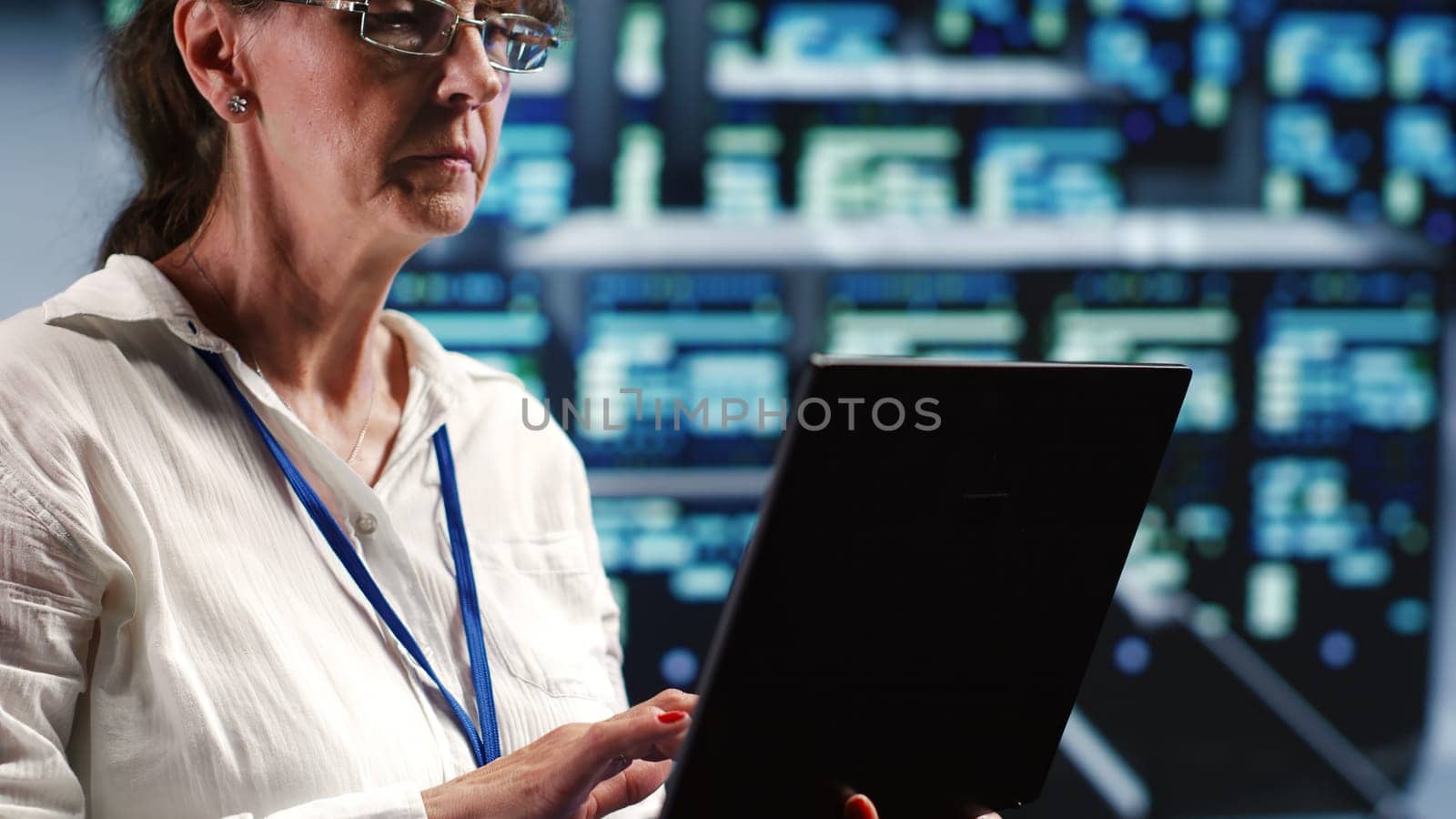 Senior technician in server room equipped to handle modern computing requirements, doing regular upgrades to components, increasing processing power and storage capacity to prevent flaws