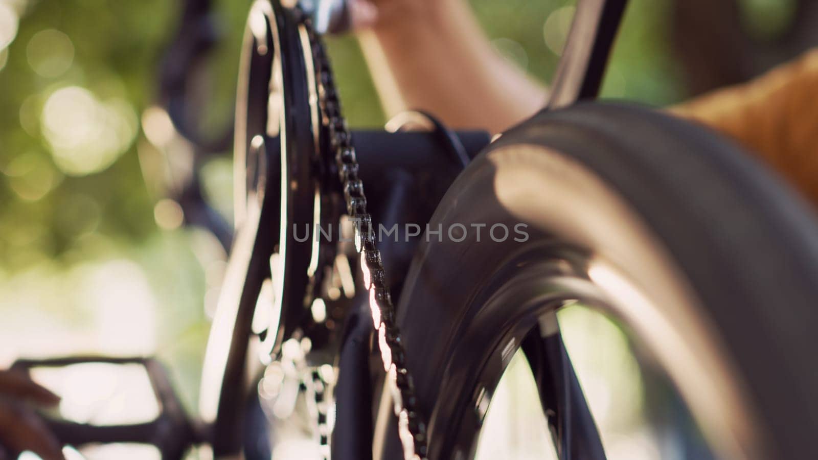 Close-up shot of two persons greasing chain of modern bicycle in home yard. Detailed view of caucasian boyfriend applying grease to bike components with the help african american girlfriend outdoor.