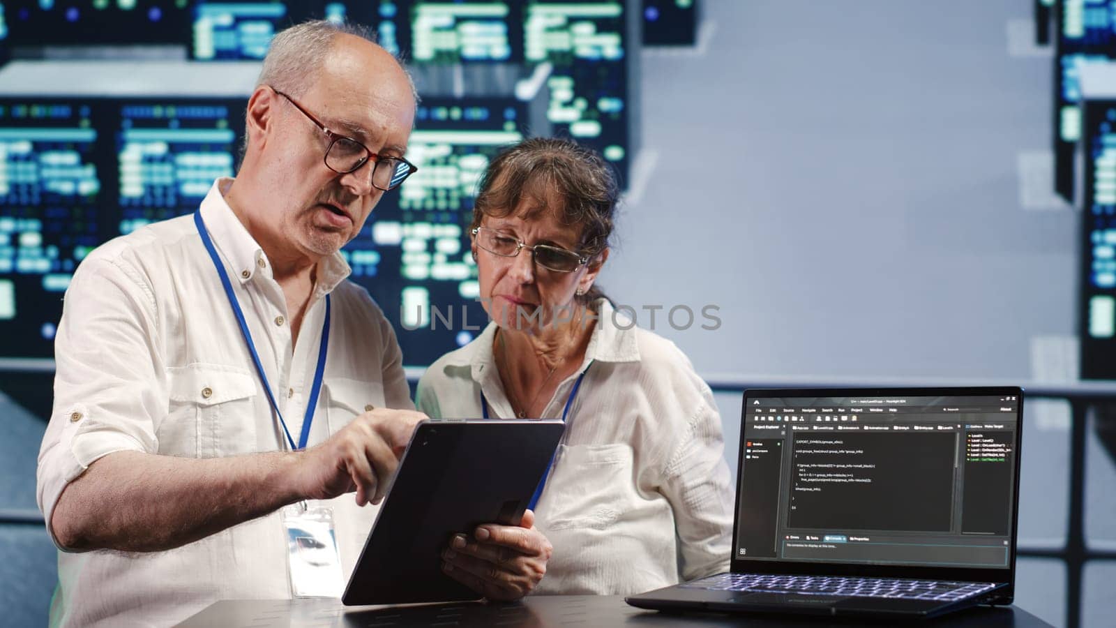 Data storage company executives solving tasks on tablet while running scripts on laptop terminal. Proficient tech support workers amidst servers, accessing databases and manipulating lines of code