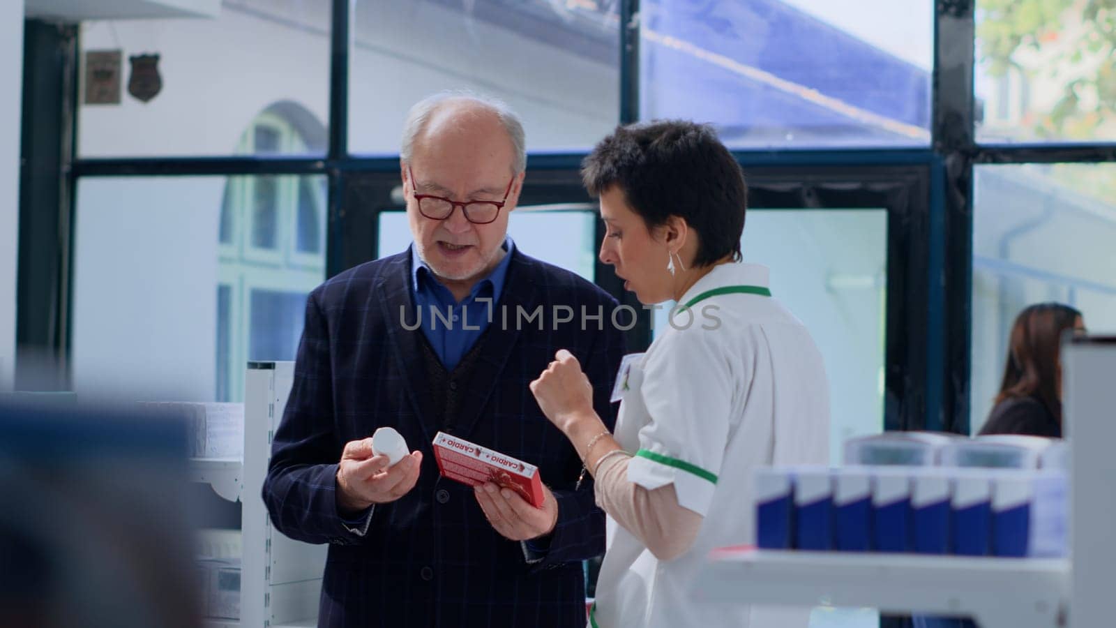 Proficient pharmacy heart specialist helping elderly man with medical suggestions. Senior client in dispensary wishing to purchase cardiologist prescribed medicaments, asking expert for guidance