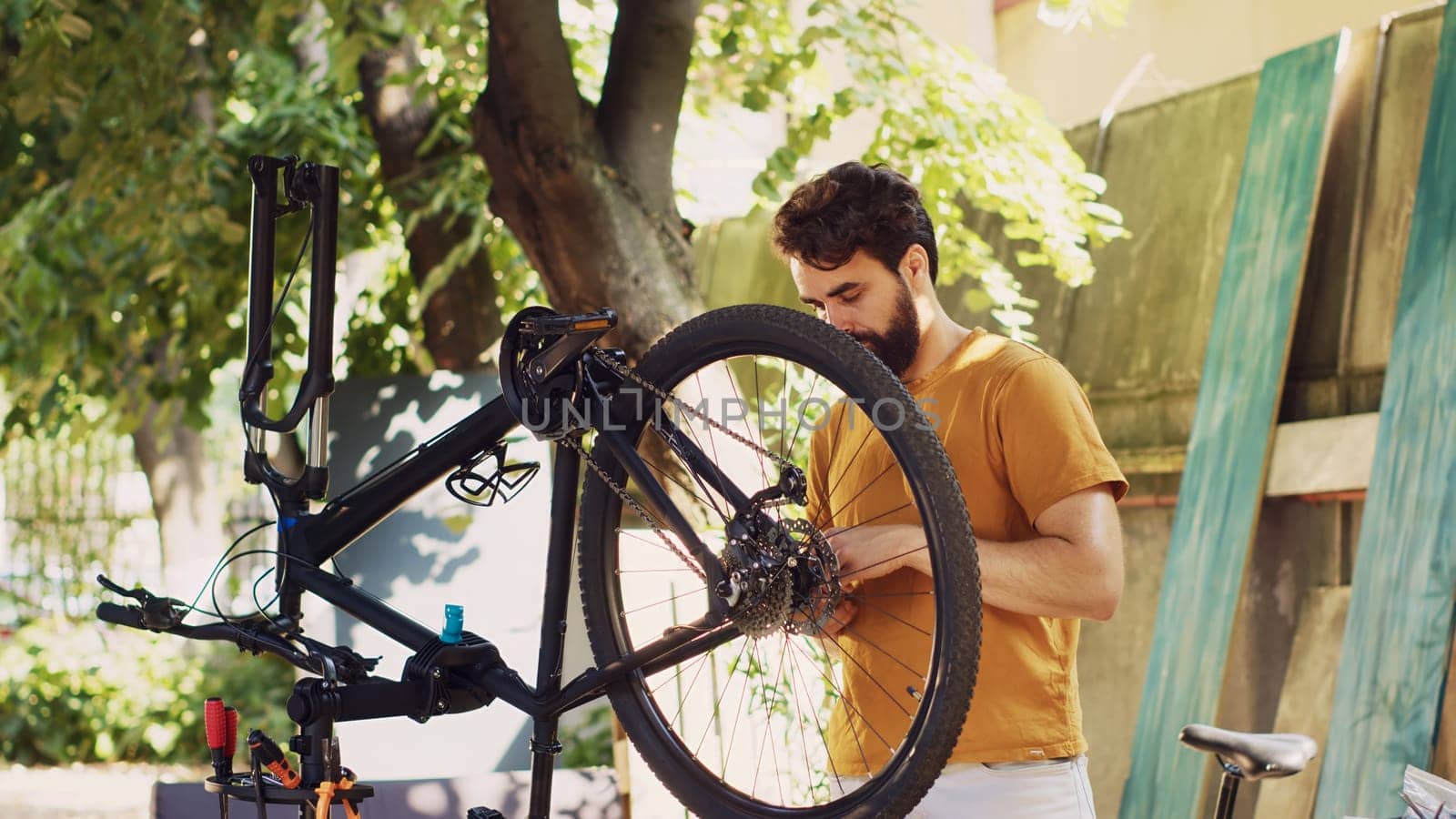 Active man outside demonstrating commitment to repairing and securing bicycle components for summer cycling leisure. Caucasian male selecting professional equipment for bike maintenance.