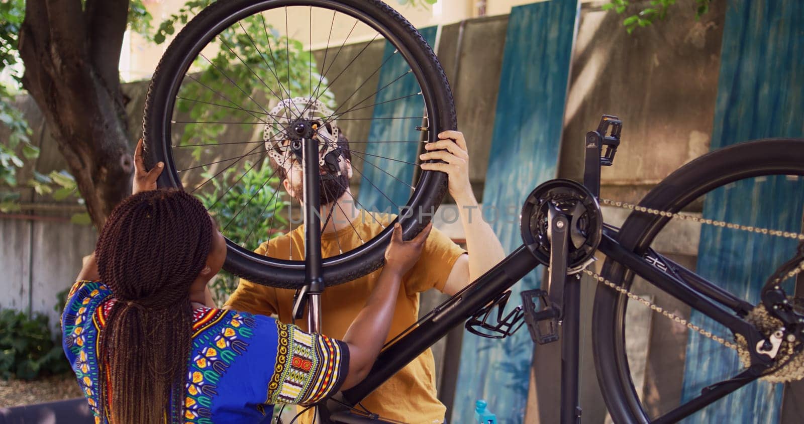 Multiracial couple maintains bike wheels by DCStudio