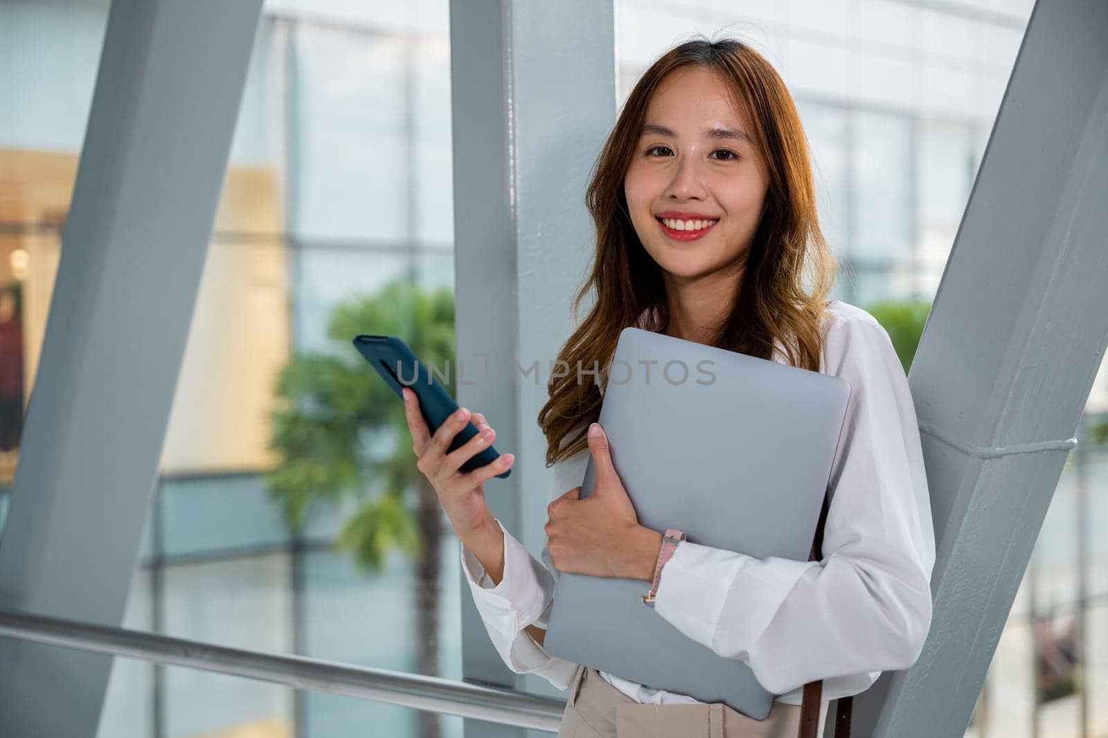 Modern businesswoman working on laptop and phone in airport by Sorapop