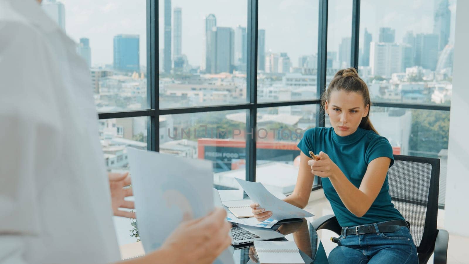 Professional female investor listening businessman present start up project statistic. Back view of businessman shows graph while manager using laptop analysis data at cityscape view. Tracery