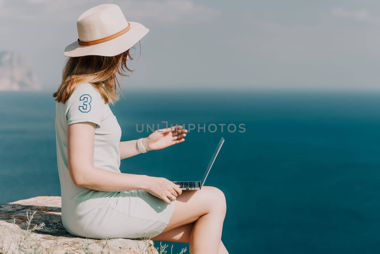 Woman sea laptop. Business woman, freelancer with laptop working over blue sea beach. Happy smiling girl relieves stress from work. Freelance, remote work on vacation, digital nomad, travel concept by panophotograph