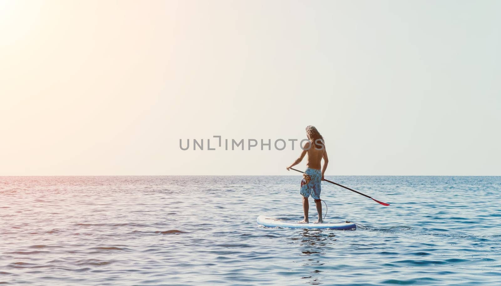 Man Sea Sup. Strong athletic man learns to paddle sup standing on board in open sea ocean on sunny day. Summer holiday vacation and travel concept. Aerial view. Slow motion.