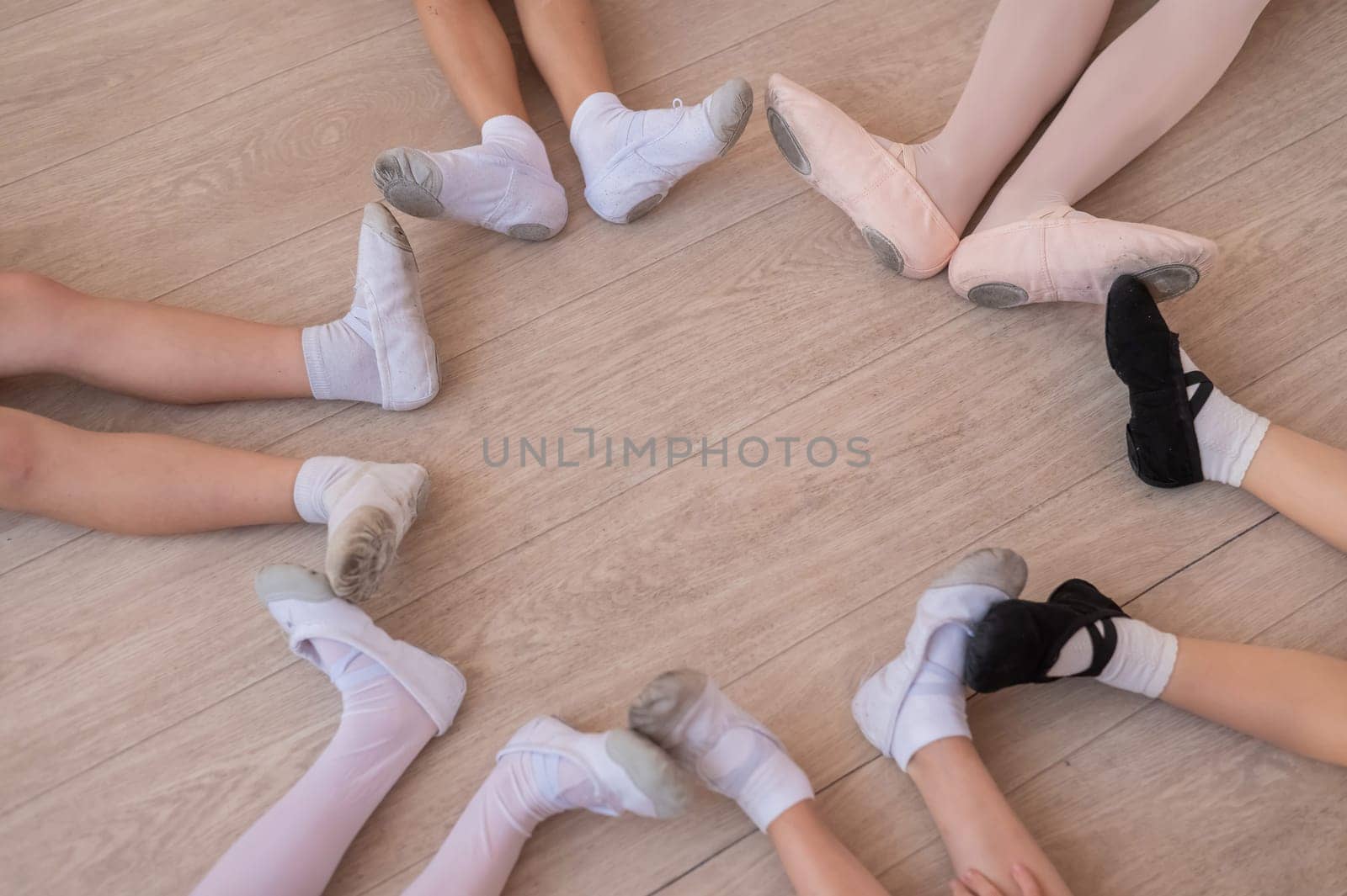 Top view of the legs of little ballerinas sitting on the floor in a circle. by mrwed54