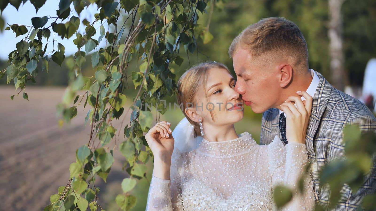 The bride and groom enjoy each other by the branches of a birch tree