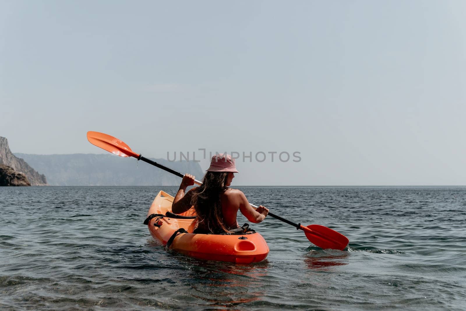 Woman sea kayak. Happy smiling woman paddling in kayak on ocean. Calm sea water and horizon in background. Active lifestyle at sea. Summer vacation. by panophotograph