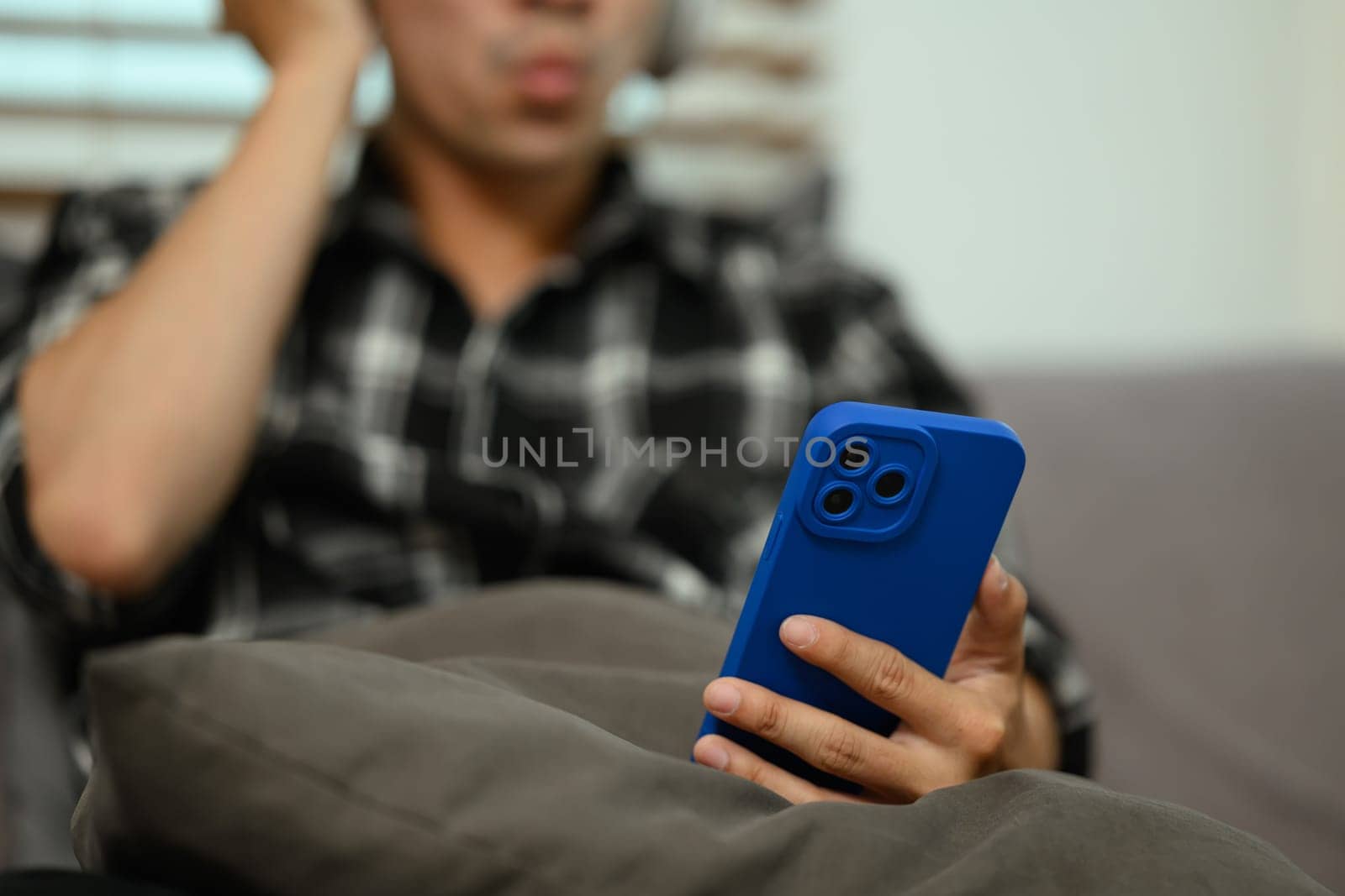 Young man listening to music with wireless headphones using mobile phone at home.