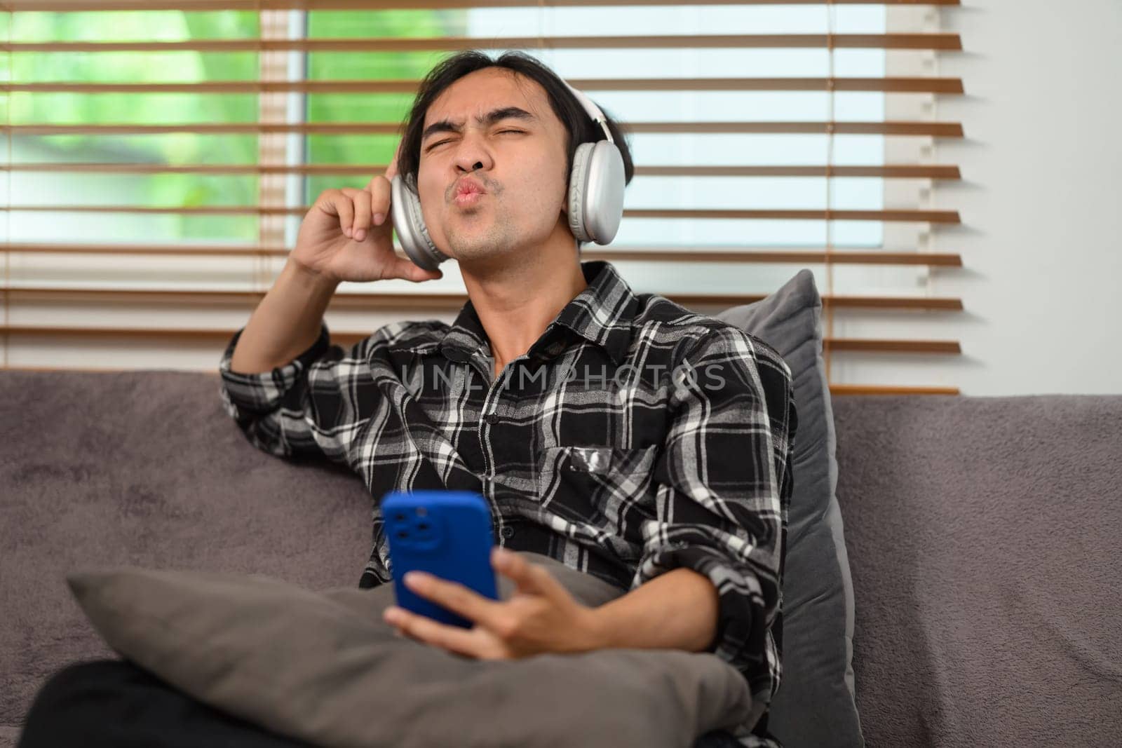 Happy young man with wireless headphones enjoying his favorite music playlist on mobile phone.