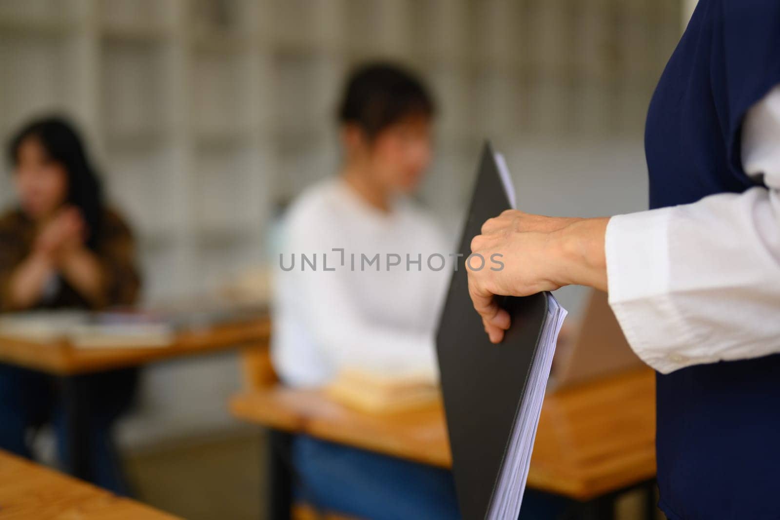 Cropped shot of professor walking around classroom while assisting her students by prathanchorruangsak