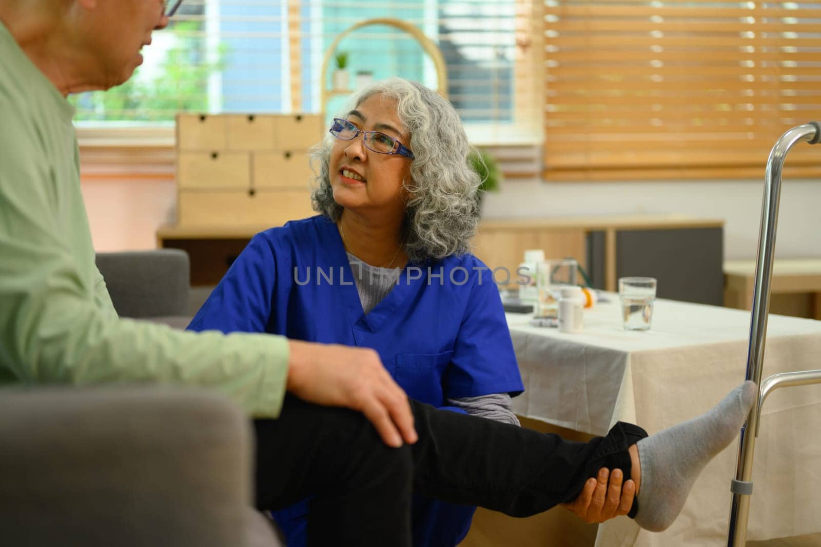 Professional physiotherapist massaging and kneading senior male patient legs by prathanchorruangsak