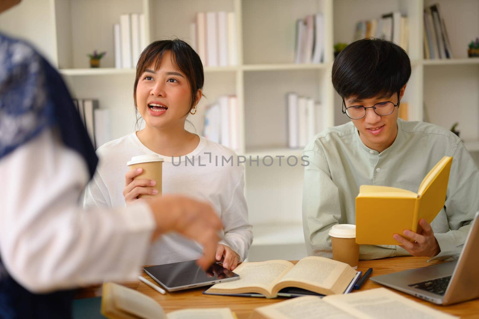 University students working on their assignment with help from teacher by prathanchorruangsak