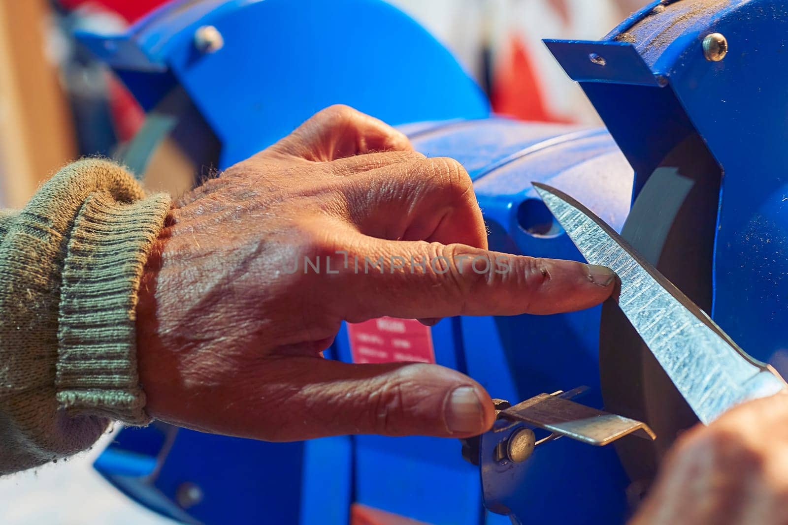 Sharpening a knife on a blue machine in the workshop by jovani68