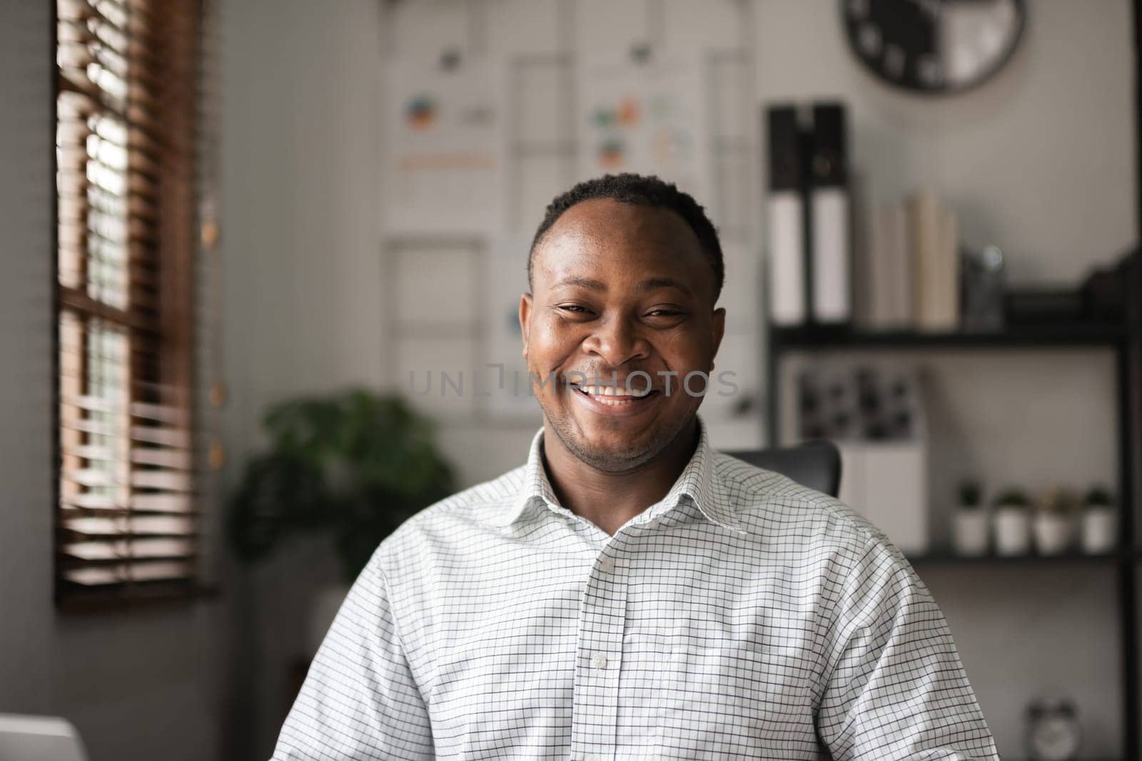 Portrait of a happy young African American businessman smiling in his home office. by wichayada