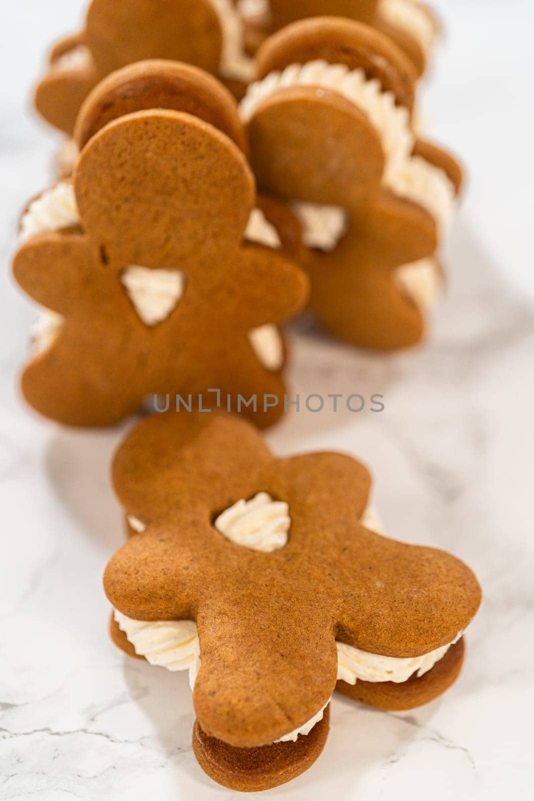 Gingerbread cookies filled with eggnog buttercream stand out, their rich hue complementing the eggnog buttercream, against a gentle background. These festive treats exude a homemade allure.