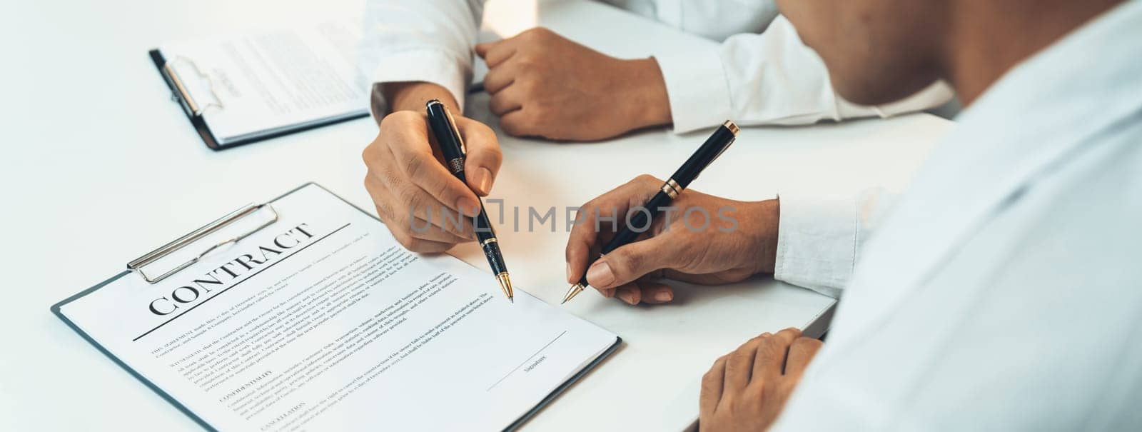 Business executive signing contract agreement document on the bale with the help from company attorney or lawyer service in law firm office. Business investing and finalizing legal processing. Shrewd