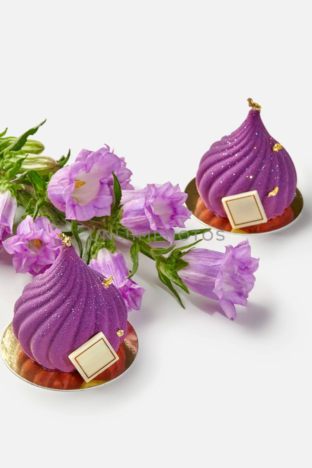 Two purple swirl-shaped pastries with flowers on white by nazarovsergey