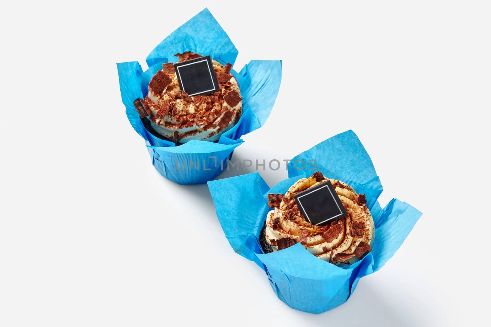 Chocolate cupcakes with whipped cream in blue paper wrappers by nazarovsergey
