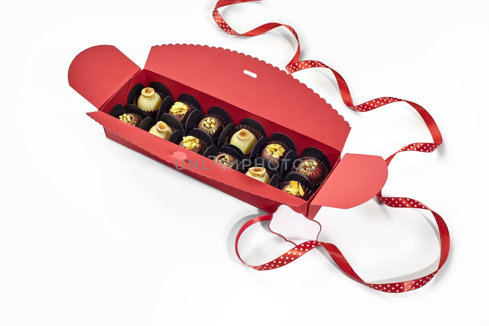 Exquisite chocolate candies in red gift box with dotted ribbon by nazarovsergey