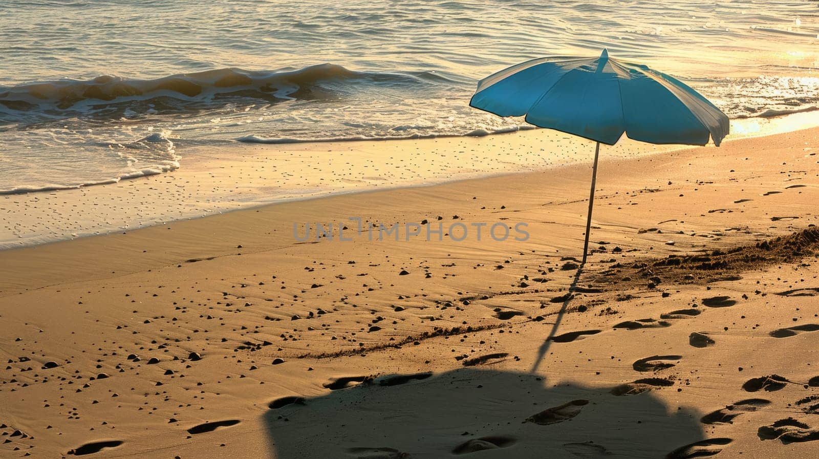 An umbrella rests on the sandy shore of the beach, overlooking the vast expanse of water. Travelers enjoy the scenic landscape as they relax on the shore AIG50