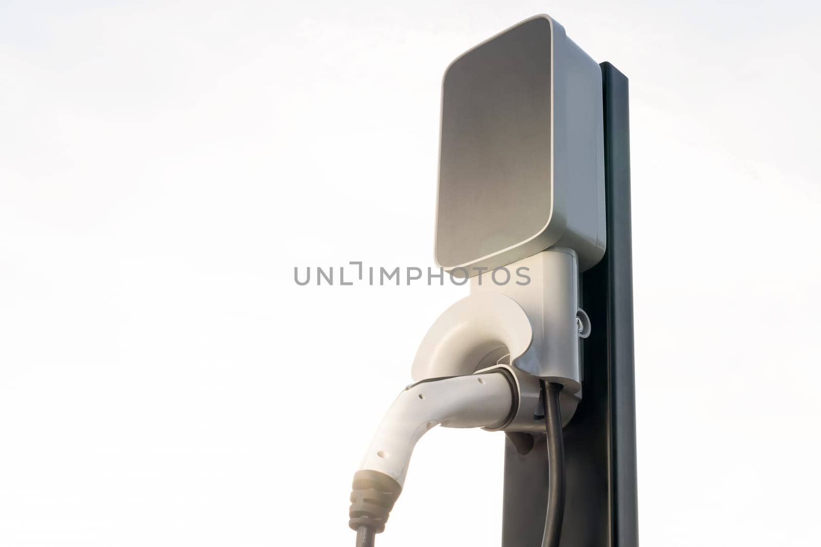 Backlit EV charging station at sunset or sunrise sky lighting, symbolizing the dawn of future eco-friendly transportation powered by clean and sustainable energy for natural protection. Exalt