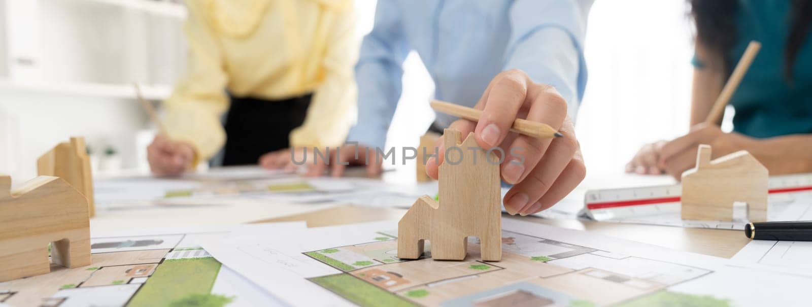 Professional architect engineer team discussion about architectural project on meeting table with wooden block and blueprint scatter around. Design and cooperate concept. Closeup. Delineation.