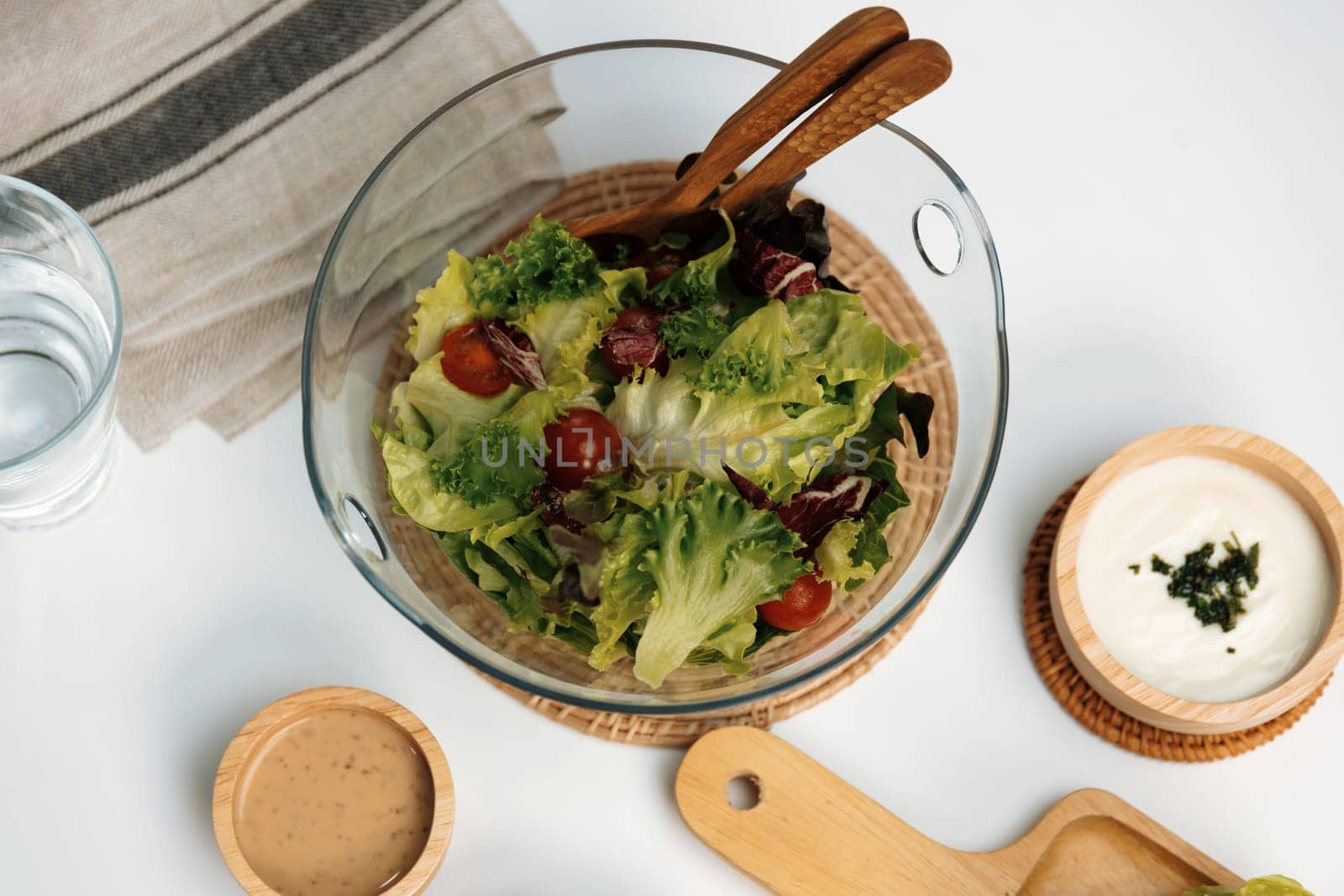 Fresh mix vegetable salad in glass blow beside dish of double meat hamburger and wholegrain bun on meal cooked by homemade serving white table. Preparing special dish menu list's restaurant. Infobahn.