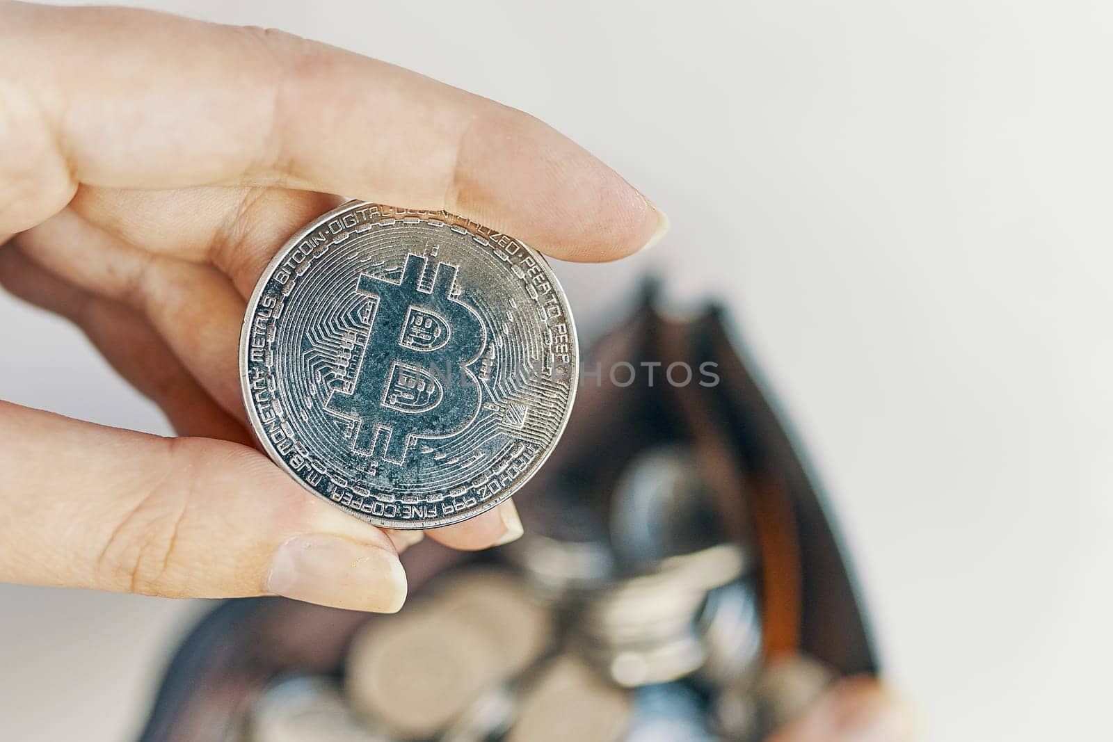 Woman holds Bitcoin coin. silver bit-coin is placed in a wallet full of coins.