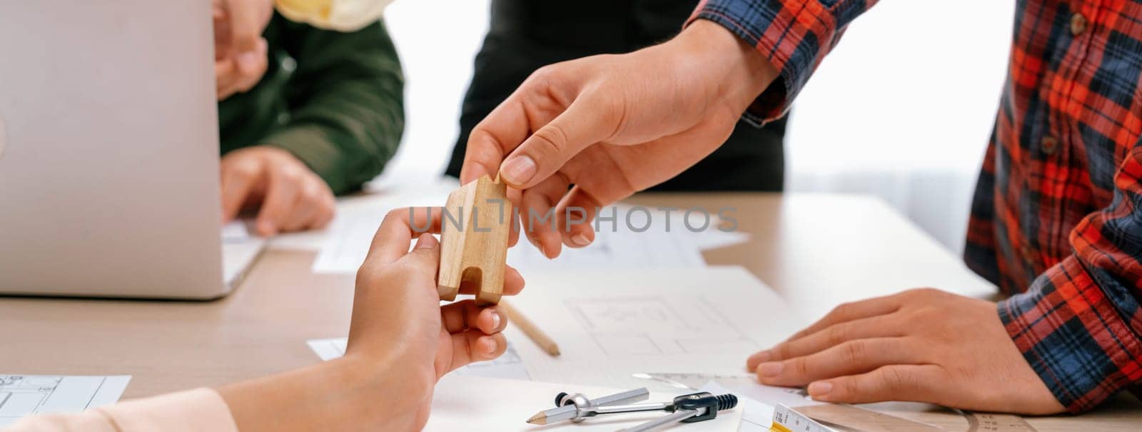 Professional architect team discussion about architectural project on meeting table with blueprint and wooden block scatter around at modern office. Closeup. Focus on hand. Delineation.