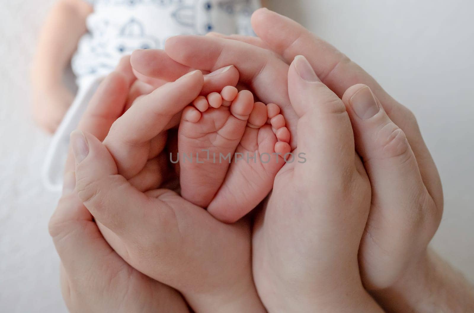 Parents Cradle Newborn Baby'S Tiny Legs In Their Hands