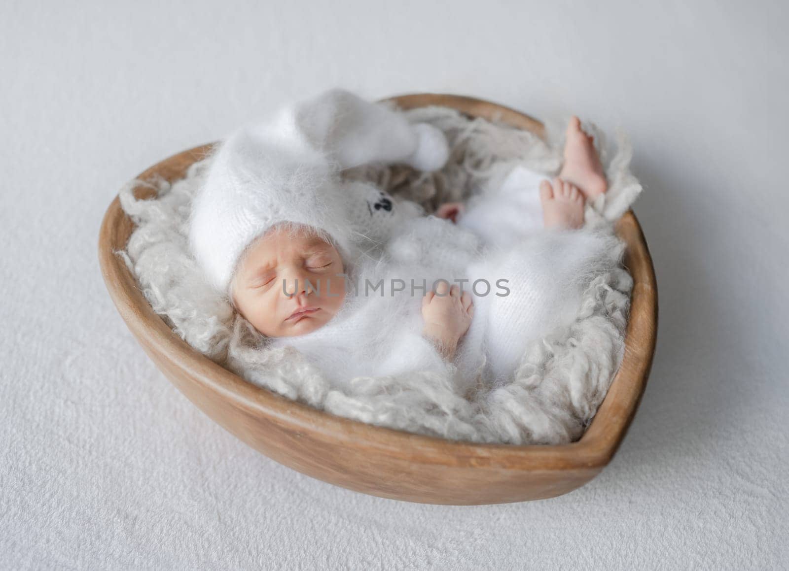 Newborn Baby In White Onesie Sleeps In Heart-Shaped Wooden Bowl by tan4ikk1