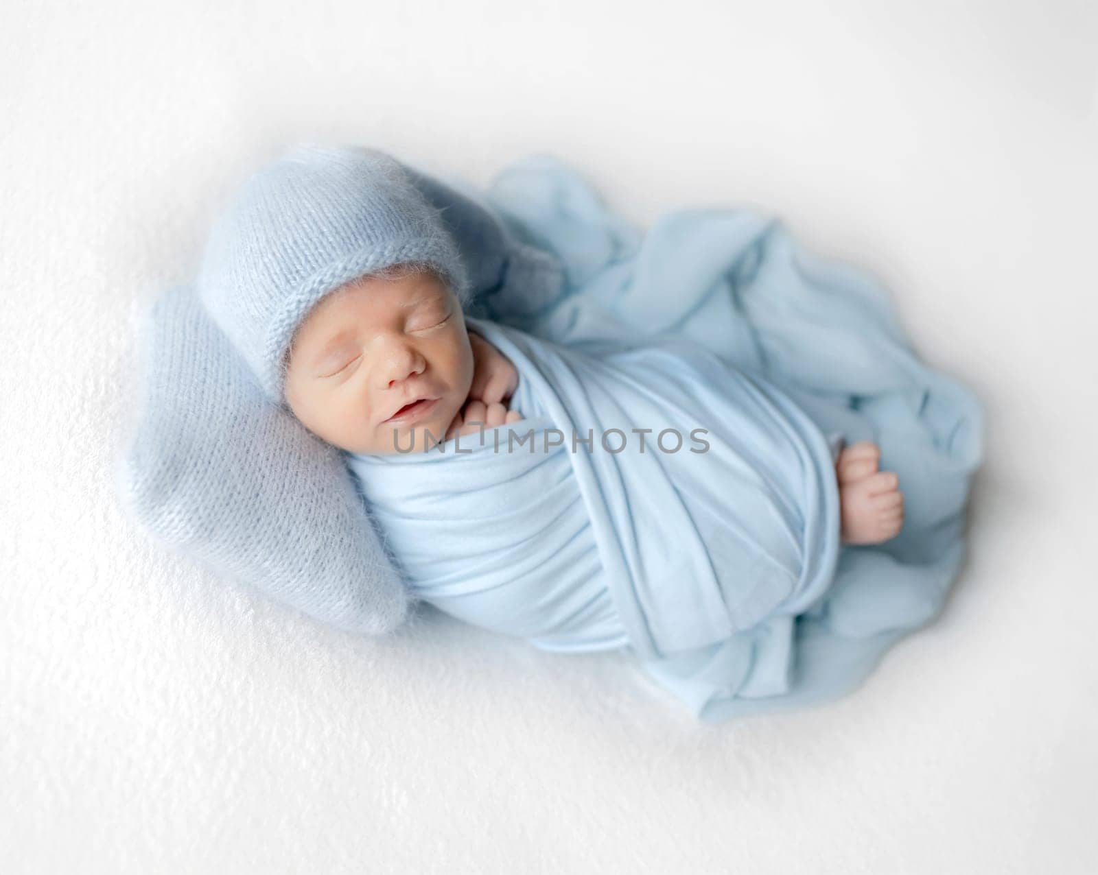 Newborn Baby In White Jumpsuit Sleeps During Studio Photoshoot