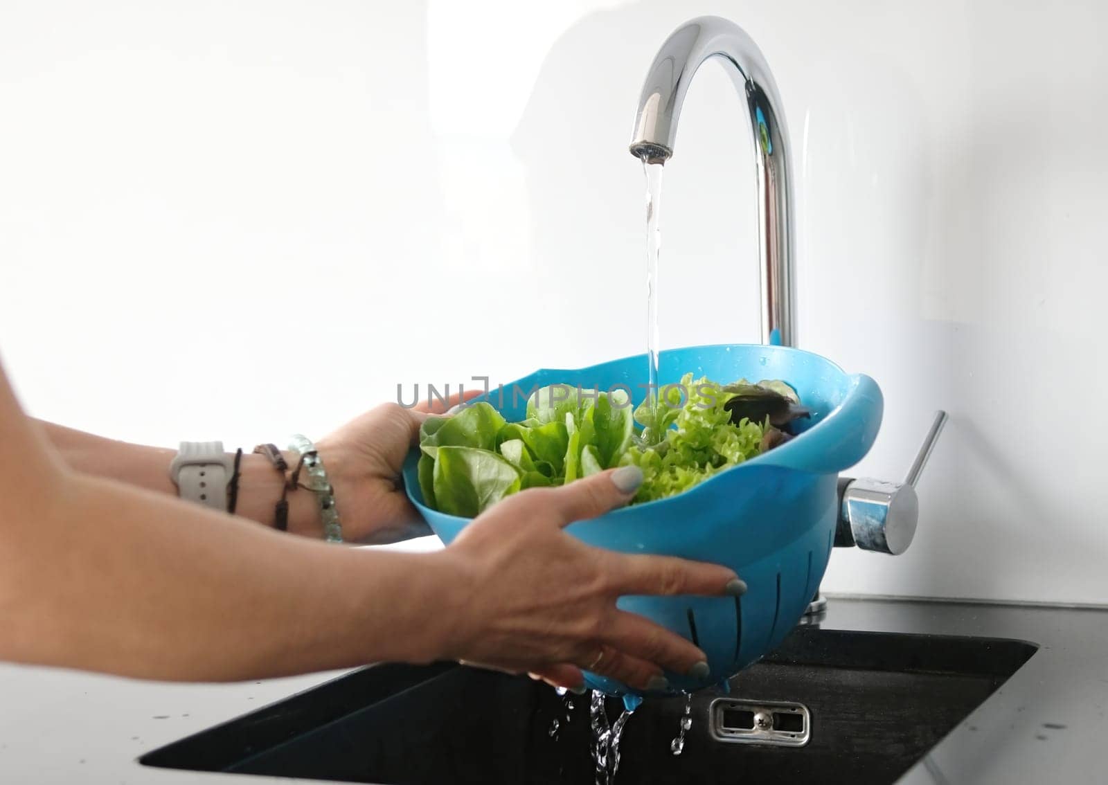 Young Woman In Kitchen Washes Lettuce Leaves In Close-Up View