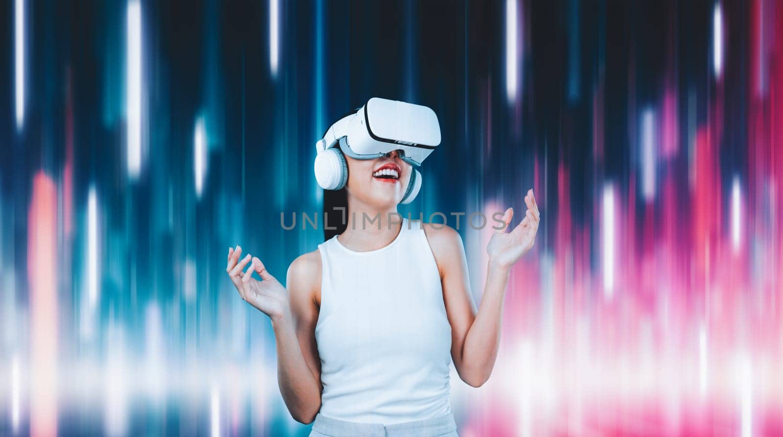 Female standing and wearing white VR headset and white sleeveless connect metaverse, future technology creating cyberspace community. She enjoy look fantasy abstract light around her. Hallucination.