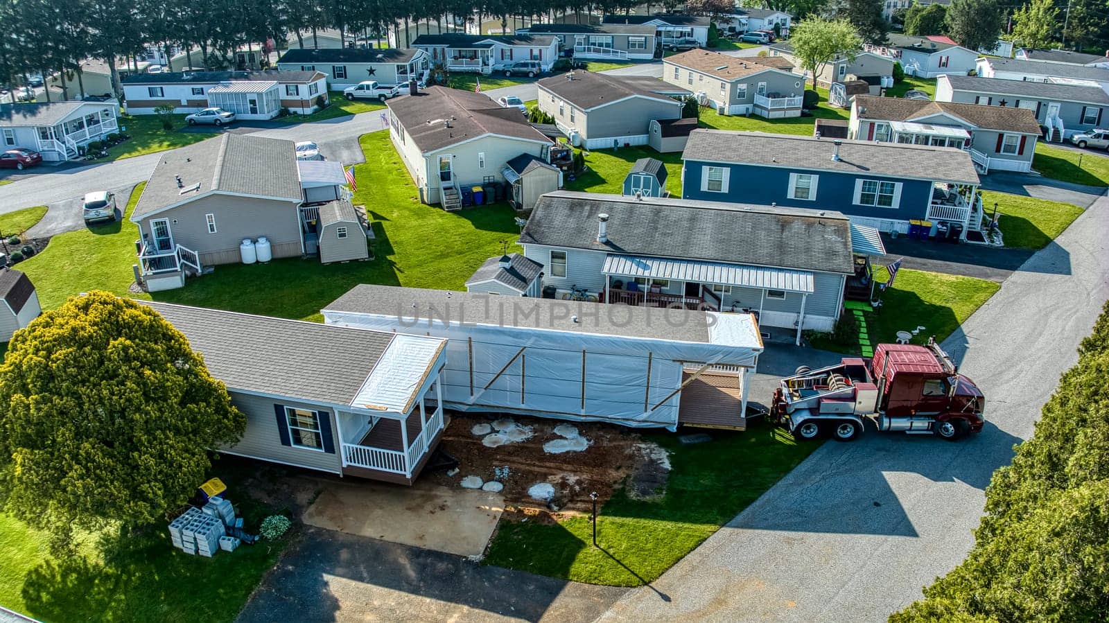 An Aerial View of a Manufactured, Mobile, Prefab Double Wide Home Being Installed in a Lot in a Park