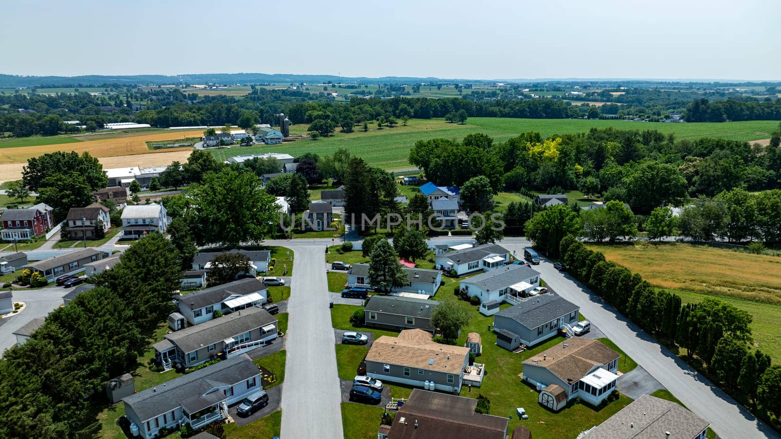 Overhead aerial view of a suburban Mobile, Prefab, Manufactured, neighborhood park, featuring rows of homes, neatly trimmed lawns, and parked cars