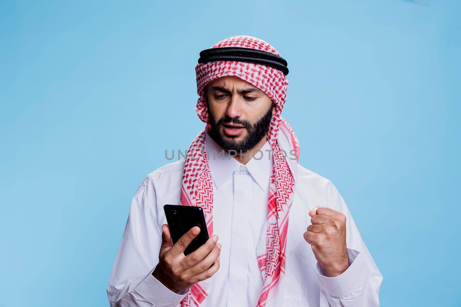 Excited arab checking message on phone by DCStudio