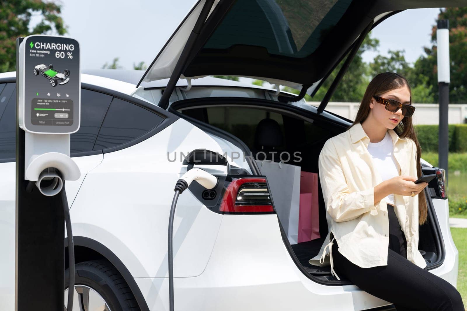 Young woman use smartphone to pay for electricity for EV car. Expedient by biancoblue