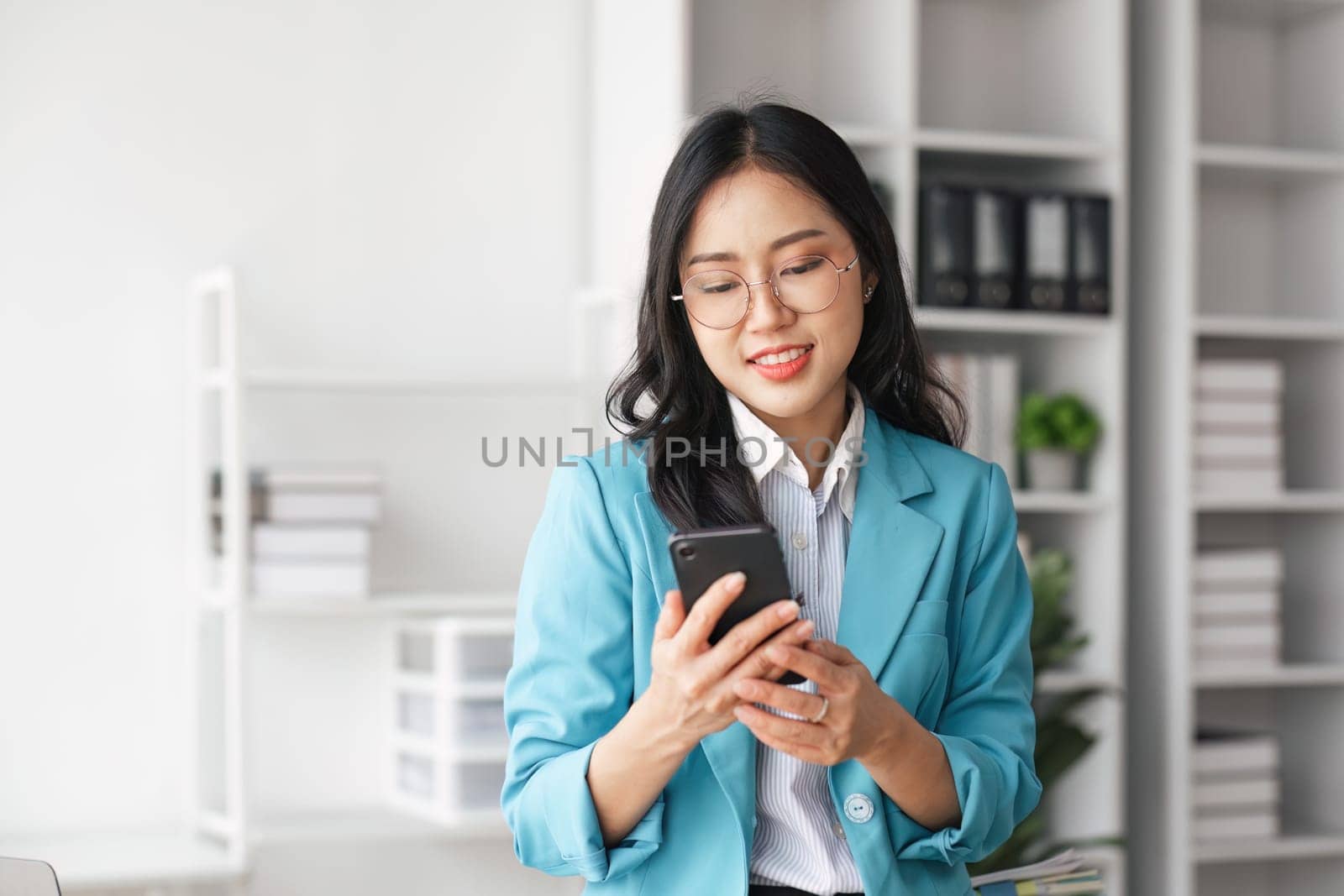 Business woman using mobile phone at a company is typing a conversation on the internet by nateemee